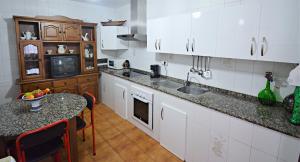 een keuken met witte kasten en een tafel en een aanrecht bij Apartamentos Caleiro 4P - Vilanova de Arousa in Villanueva de Arosa