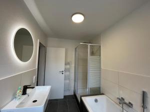 y baño con lavabo, bañera y espejo. en Ferienhaus Bodensee - by Heinke Wohnraum, en Oberteuringen