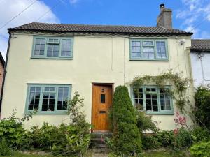 a white house with a wooden door and windows at Elm Cottage in Northallerton