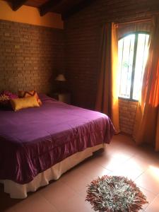 1 dormitorio con cama morada y ventana en La cabañita de Maco en Nono