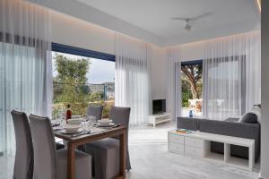 a dining room with a table and chairs and a couch at Augoustos ECO luxury apartments with pool in Aghia Marina