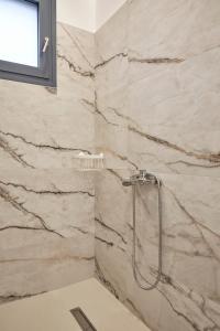 a shower in a bathroom with marble walls at Augoustos ECO luxury apartments in Aghia Marina