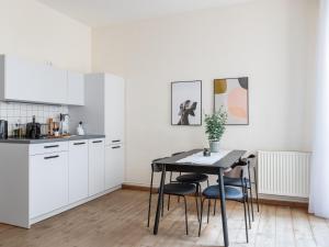 a kitchen with white cabinets and a table and chairs at Schoenhouse Avenue - Digital Access in Berlin