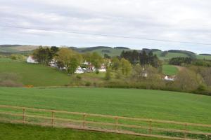 un campo verde con una valla y casas a lo lejos en Keith View, Humbie Hub, en Humbie