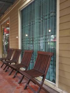 three wooden chairs sitting on a porch near a window at นอนในสวน รีสอร์ท in Bangkok