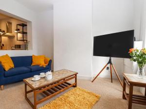 ein Wohnzimmer mit einem blauen Sofa und einem TV in der Unterkunft Castle Cottage in Hythe