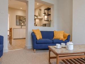 a living room with a blue couch and a table at Castle Cottage in Hythe