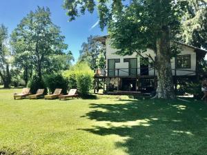 una casa con un árbol y sillas en el patio en El Limbo Posada en Tigre