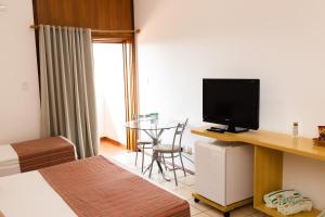 a room with a bed and a desk with a television at Hotel Cabreúva Resort in Cabreúva