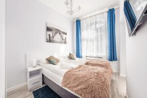 een slaapkamer met een bed en een raam met blauwe gordijnen bij Apartamenty Sun & Snow Na Monte Cassino in Sopot