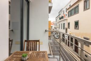a balcony with a wooden table and a view of a street at Anadia Atrium F in Funchal