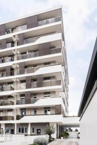 un edificio de apartamentos alto y blanco con aparcamiento en SUITE GENTILE en Bari