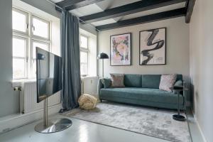 ein Wohnzimmer mit einem Sofa und einem TV in der Unterkunft Unique 2 Bedroom Duplex w Exposed Beams in CPH City in Kopenhagen
