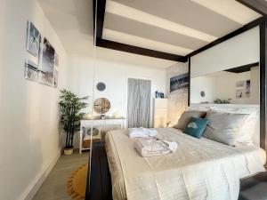 - une chambre avec un grand lit blanc et des oreillers bleus dans l'établissement Rêve de plage - Confortable appt pour 2, à Canet