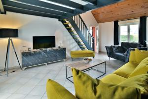 a living room with a couch and a tv at Maison Victoria - avec piscine in Plédèliac