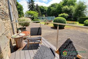 een balkon met stoelen, een tafel en een leuning bij Chambres d'hôtes - Au Domaine des Camélias in Pluméliau