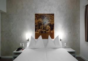 a bedroom with a white bed with a painting on the wall at Acquarello Swiss Quality Hotel in Lugano