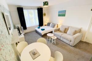 a living room with a couch and a bed and a table at The Chine- A Spacious Studio Close to the Beach in Bournemouth