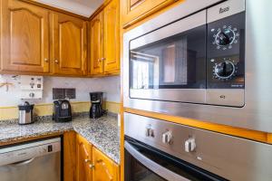 a kitchen with wooden cabinets and a stainless steel microwave at Villa Estrelícia - Pool - Free wi-fi - New in Booking in Loulé