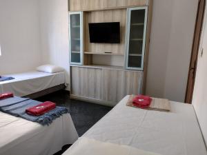 a room with two beds and a flat screen tv at Hotel Chalé Da Prata in Curvelo