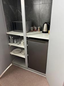 a kitchen with a shelf with dishes and a microwave at Ataria Place in Cradock