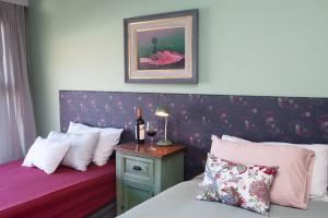 1 dormitorio con 2 camas y mesa con botellas de vino en Las Bayas Home Suites en Esquel