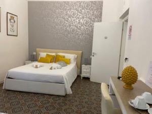 um quarto com uma grande cama branca com almofadas amarelas em Sleep Inn Catania rooms - Affittacamere em Catânia