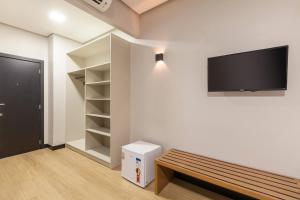 a room with a bench and a tv on the wall at Tri Hotel Antônio Prado in Antônio Prado