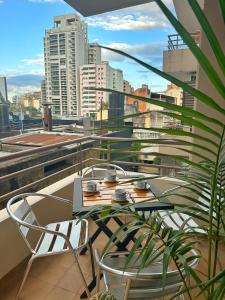 einen Tisch und Stühle auf einem Balkon mit Stadtblick in der Unterkunft Paramont Tucuman in San Miguel de Tucumán