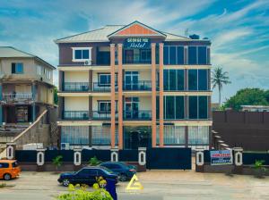 un grand bâtiment avec des voitures garées devant lui dans l'établissement GEORGE VEE HOTEL LTD, à Kumasi