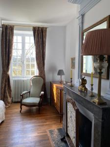 a living room with a fireplace and a chair and a mirror at Chateau La Rochette in Lisle