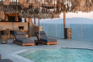 a patio with a pool and chairs and a table at Makani Suites in Ano Mera
