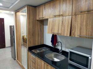 a kitchen with wooden cabinets and a sink and a microwave at Happy Home in Hurghada