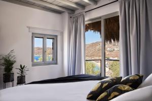 a bedroom with a bed and a large window at Boheme Beach Houses in Elia Beach