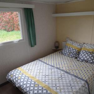 1 dormitorio con cama y ventana en CAMPING LE BEL AIR mobil home LE PALMIER 4 personnes, en Limogne-en-Quercy