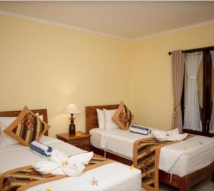 烏布的住宿－Buana Ubud Inn，酒店客房,配有三张带鲜花的床