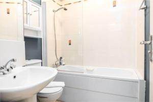 a white bathroom with a sink and a toilet and a shower at Artist's CENTRAL apartment! in Dublin