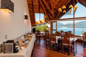 a dining room with tables and chairs and a view of the water at Hosteria La Camila in Villa La Angostura