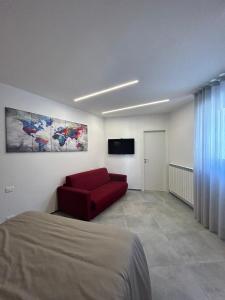 een slaapkamer met een rode bank en een flatscreen-tv bij J. Suite in Castel di Sangro