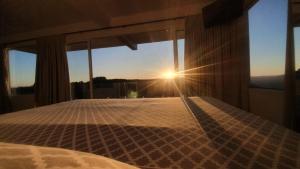 Un dormitorio con una cama con el sol brillando a través de la ventana en Cabana Morada do Vento, en Nova Petrópolis