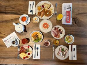 a wooden table topped with plates of breakfast food at Best Western Plus Hôtel Le Rhénan & Restaurant Chez Claude in Dorlisheim