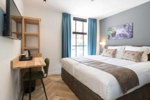 a bedroom with a bed and a desk and a window at Hof van Holland Hotel in Edam