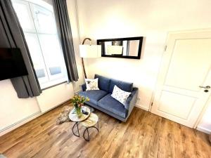 ein Wohnzimmer mit einem blauen Sofa und einem Tisch in der Unterkunft Kapitänshaus Lassen - Zimmer Mendoza in Westerland