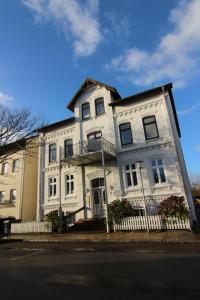 une maison blanche avec une clôture devant elle dans l'établissement Kapitaenshaus-Lassen-Zimmer-Mendoza, à Westerland