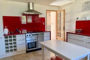 a red kitchen with a stove and a table at Magnificent 17th property calm and relaxation in Bailleau-lʼÉvêque