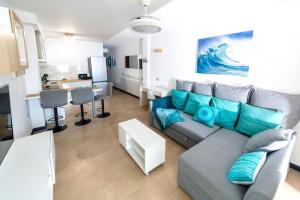 a living room with a gray couch and blue pillows at Calypso II by Sea You There Fuerteventura in Cotillo