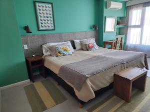 1 dormitorio con 1 cama grande y paredes verdes en Las Bayas Home Suites en Esquel