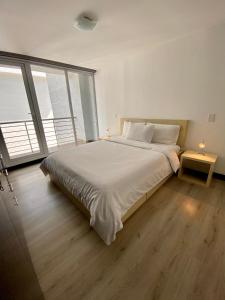 a white bedroom with a large bed and a large window at Aqua Loft in Quito