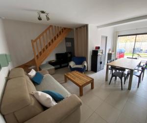 ein Wohnzimmer mit einem Sofa und einem Tisch in der Unterkunft Gîte Cala Verde Jardin, à 4km de la première plage in Audenge