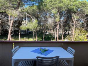 una mesa blanca y sillas en un balcón con árboles en La casa delle janas, en Platamona